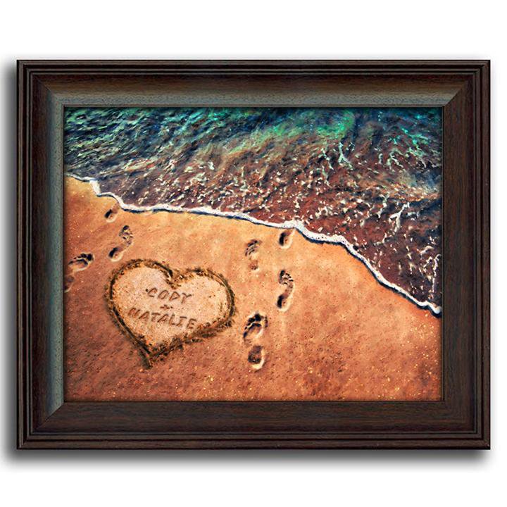 Romantic coastal beach decor with footprints in the sand and names in heart- framed behind glass